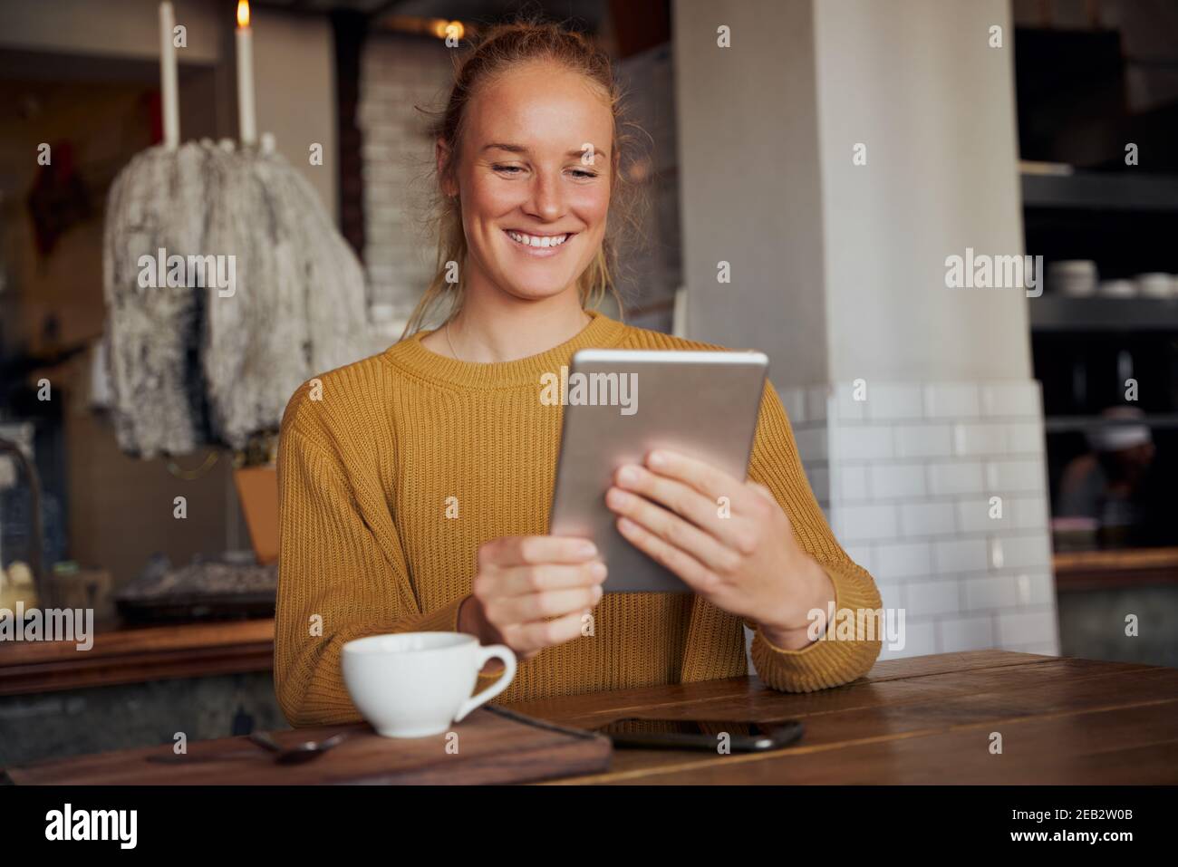 Portrait von lächelnden jungen Unternehmer sitzen in modernen Café mit Digitales Tablet Stockfoto