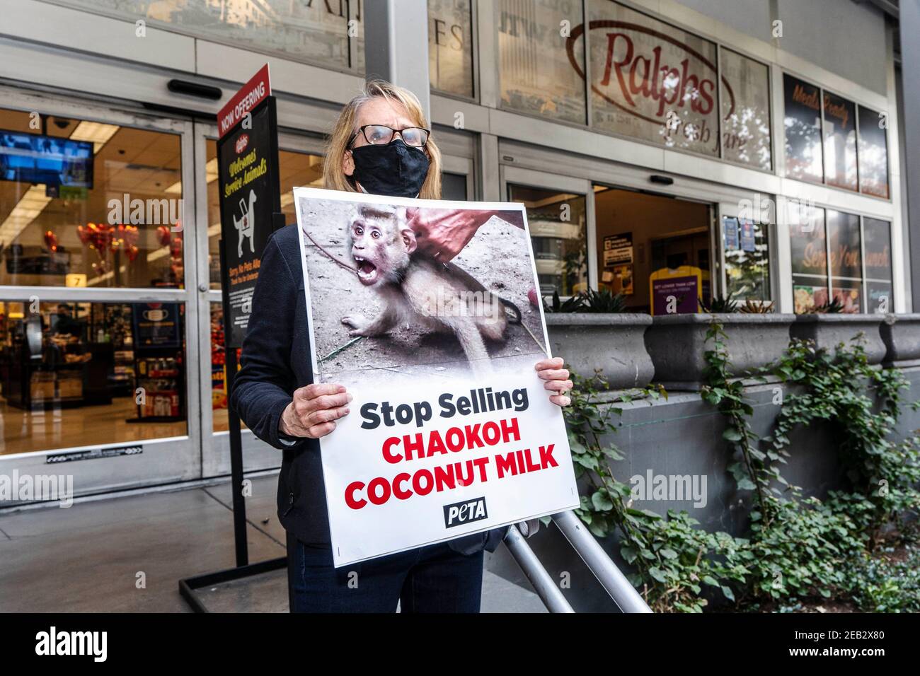 Los Angeles, Kalifornien, USA. November 2020, 16th. PETA-Aktivist hält ein Plakat während eines Protestes gegen Thailands Chaokoh-Marke, weil sie angeblich Affen dazu gezwungen haben, auf Bäume zu klettern, Kokosnüsse zu sammeln und sie unter grausamen Bedingungen zu halten. Große US-Einzelhändler wie Costco und Target stoppten den Verkauf von Chaokoh Kokosmilch über Vorwürfe der Zwangsarbeit von Affen. Kredit: Ronen Tivony/SOPA Images/ZUMA Wire/Alamy Live Nachrichten Stockfoto