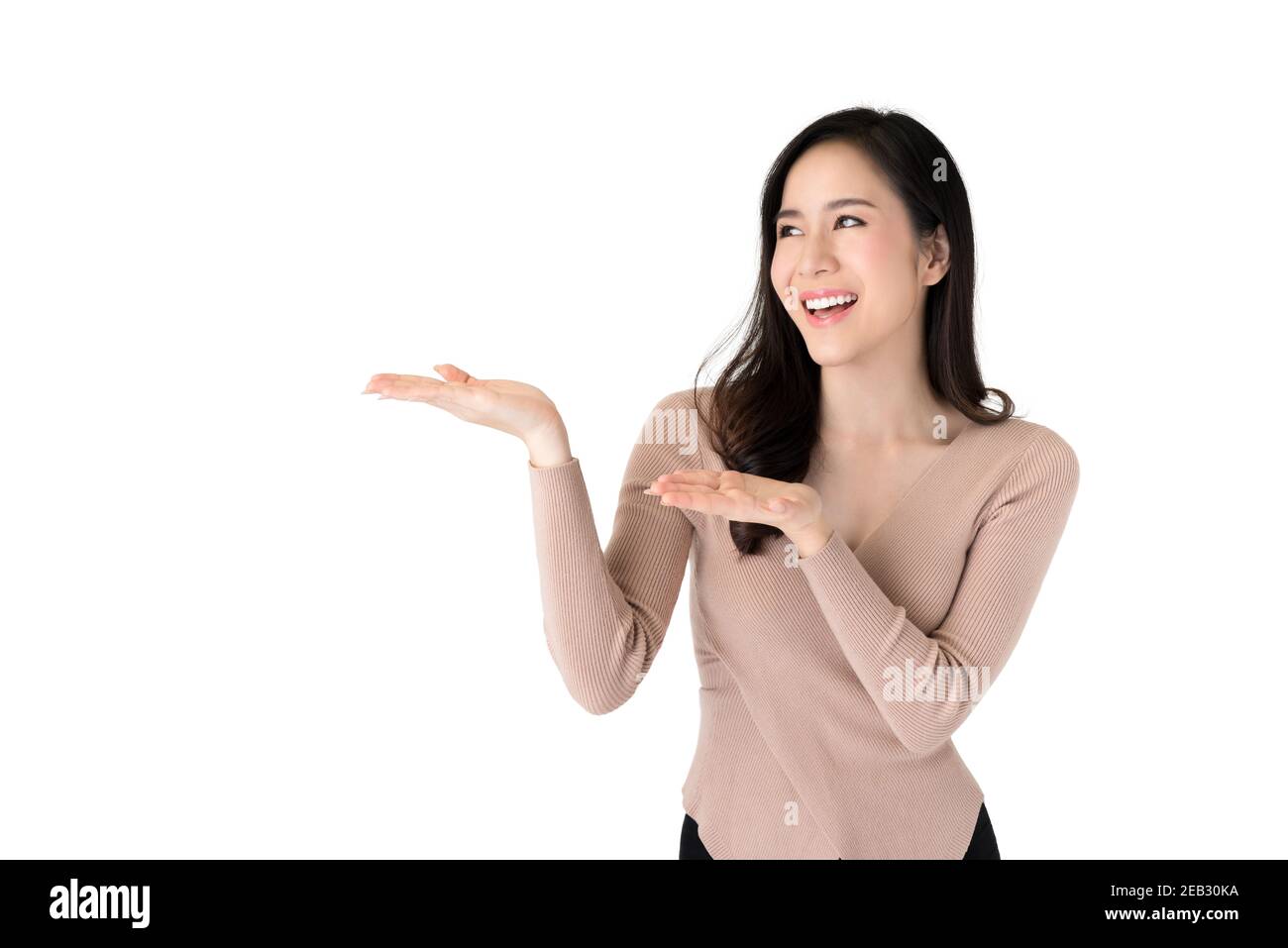 Portrait von glücklich lächelnd junge schöne asiatische Frau in casual Kleidung in einer präsentierenden Geste mit beiden Armen angehoben und Palmen öffnen in weiß isolieren Stockfoto