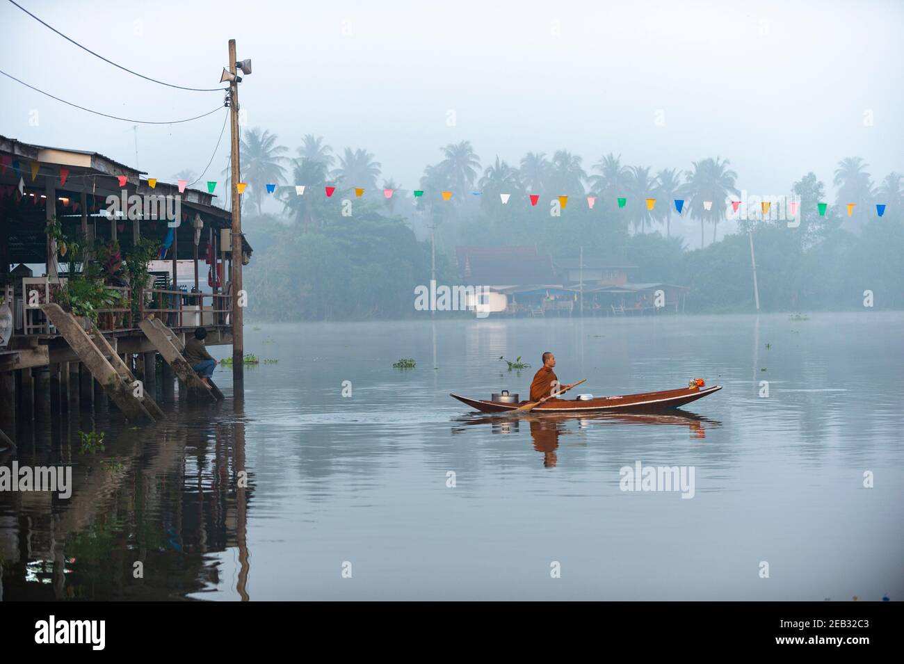 Samut Songkhram / Thailand - Feb 22 2015 : der Mönch saß auf einem Ruderboot um Almosen an einem Kanal in Amphawa im Morgennebel. Frisch und wunderschön Stockfoto