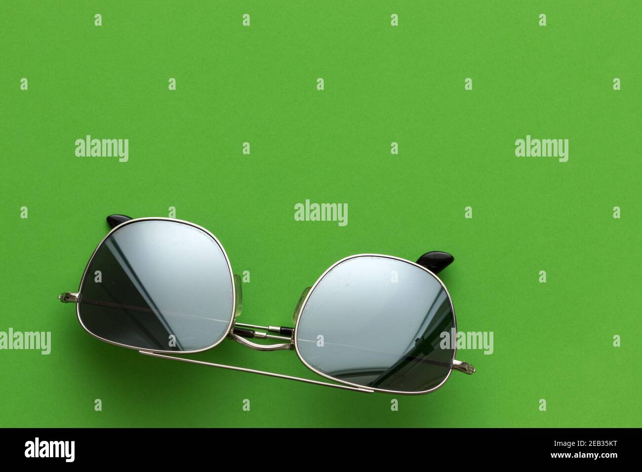 Silberne Sonnenbrille aus Metall, auf grünem Hintergrund Stockfoto