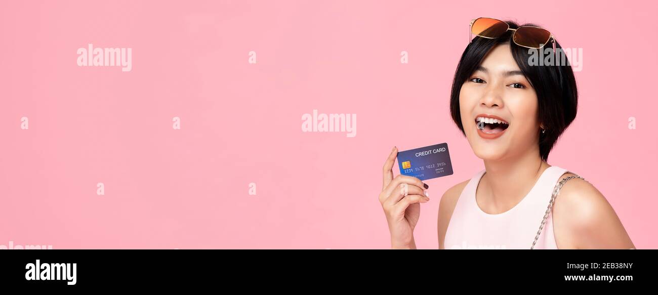 Junge hübsche asiatische Frau zeigt Kreditkarte in Hand Studio Aufnahme isoliert auf rosa Banner-Hintergrund mit Kopierplatz Stockfoto