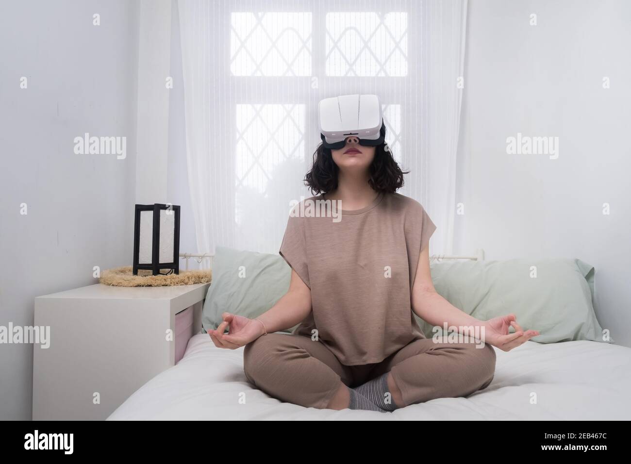 Junge Frau mit vr Brille. Freizeitbeschäftigung zu Hause virtuelle  Realität. Yoga-Meditation. Weißes Schlafzimmer Stockfotografie - Alamy