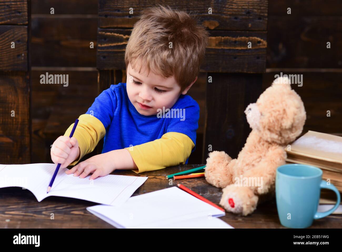 Konzentriertes Kind Schüler Zeichnung. Beschäftigte Kinder schreiben im Übungsbuch. Stockfoto