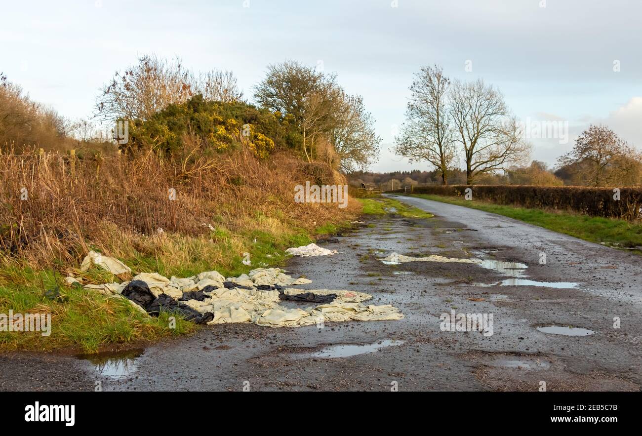Die Verschmutzung der landwirtschaftlichen Kunststoffabfälle wurde an der Seite einer Landstraße, neben dem Tor zu einem Feld, hinterlassen Stockfoto