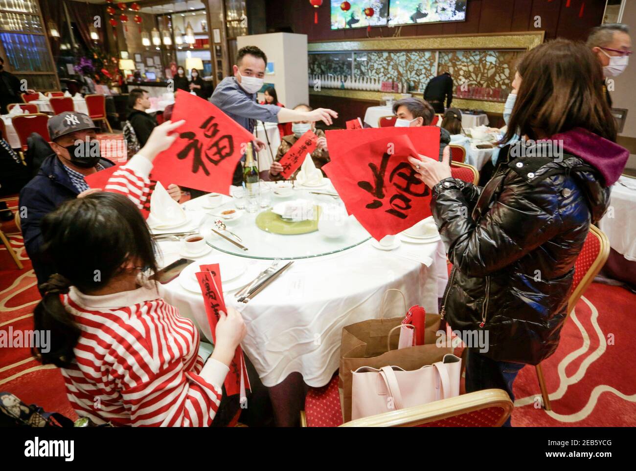 Richmond, Kanada. Februar 2021, 11th. Die Menschen tauschen sich während des Abendessens zum chinesischen Neujahrsfest in einem Restaurant in Richmond, British Columbia, Kanada, am 11. Februar 2021 über chinesische Fu-Muster aus, was Glück bedeutet. Quelle: Liang Sen/Xinhua/Alamy Live News Stockfoto