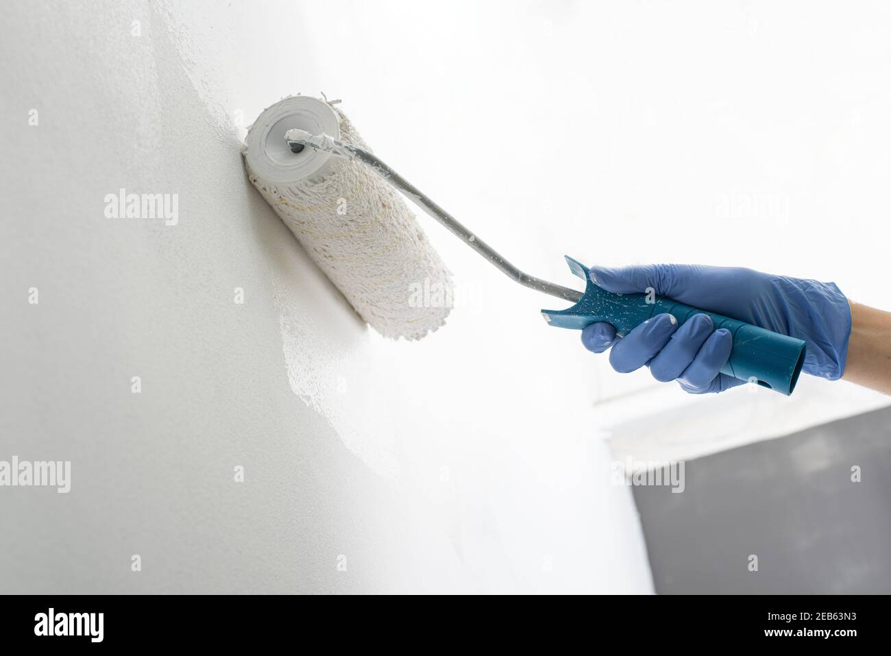 Nahaufnahme einer Hand Malerei Wand weiß mit einer Rolle Stockfoto
