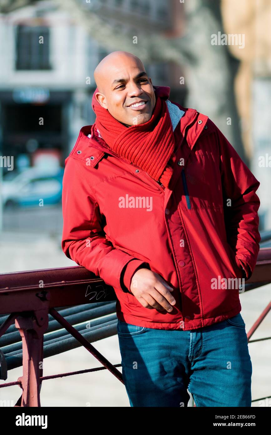 Glücklich lächelnder Hipster Hispanic männlich lehnt auf einem Metallgeländer in einer Straße von Lyon, Frankreich Stockfoto