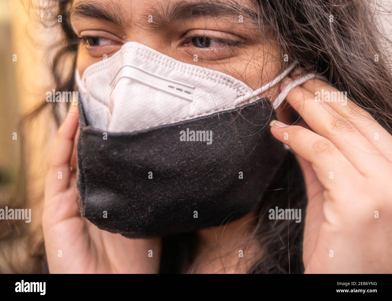 Indische Frau trägt zwei Gesichtsmasken, eine N95 und eine Stoffmaske für covid-19 Prävention. Vorderansicht. Doppelmaskierung wird von der US CDC vorgeschlagen. Stockfoto