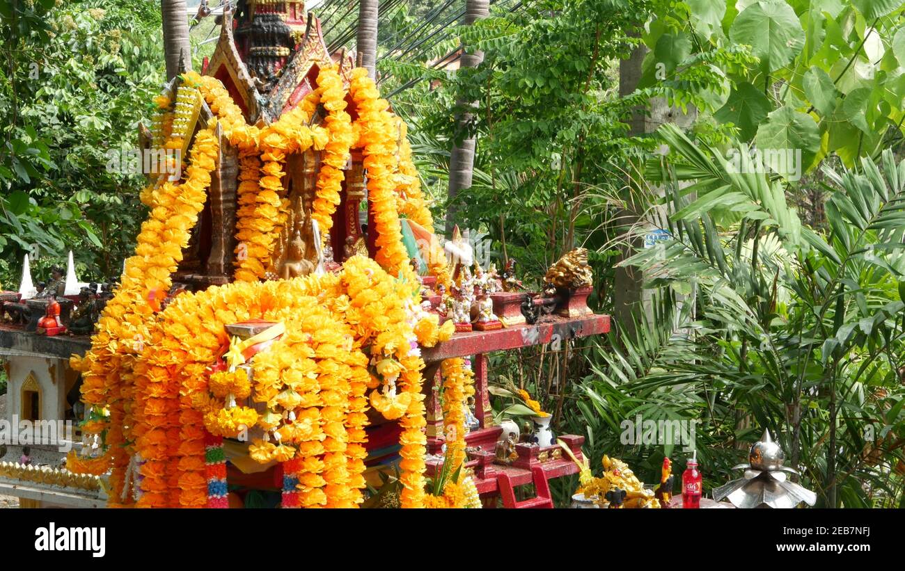 Hölzerne Miniatur Wächter Geist Haus. Kleiner buddhistischer Tempelschrein, bunte Blumengirlanden. San phra phum errichtet, um Glück zu bringen. Traditionelle RE Stockfoto