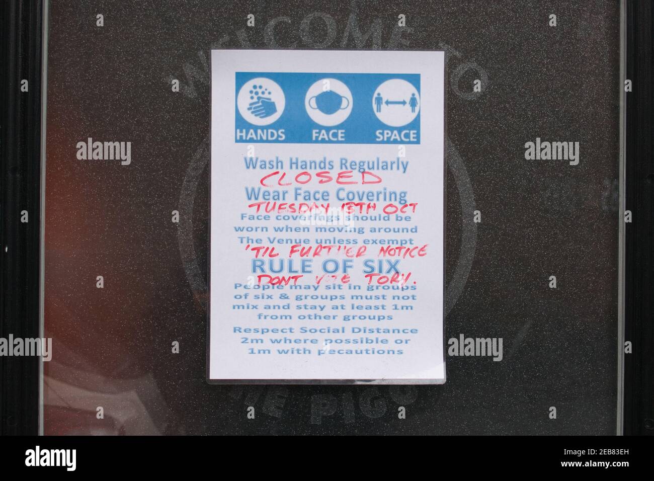 Ein Schild hinter dem Fenster einer Kneiptür weist darauf hin, dass die Kneipe während der COVID-Sperre in Großbritannien bis auf weiteres geschlossen ist. Die Bekanntmachung auch Auto Stockfoto