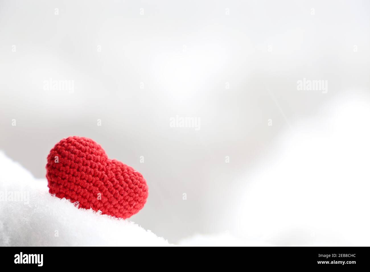 Liebe Herz im Schnee, Hintergrund für Valentinstag-Karte mit verschwommenem Kopierplatz. Rot gestricktes Symbol der romantischen Liebe Stockfoto