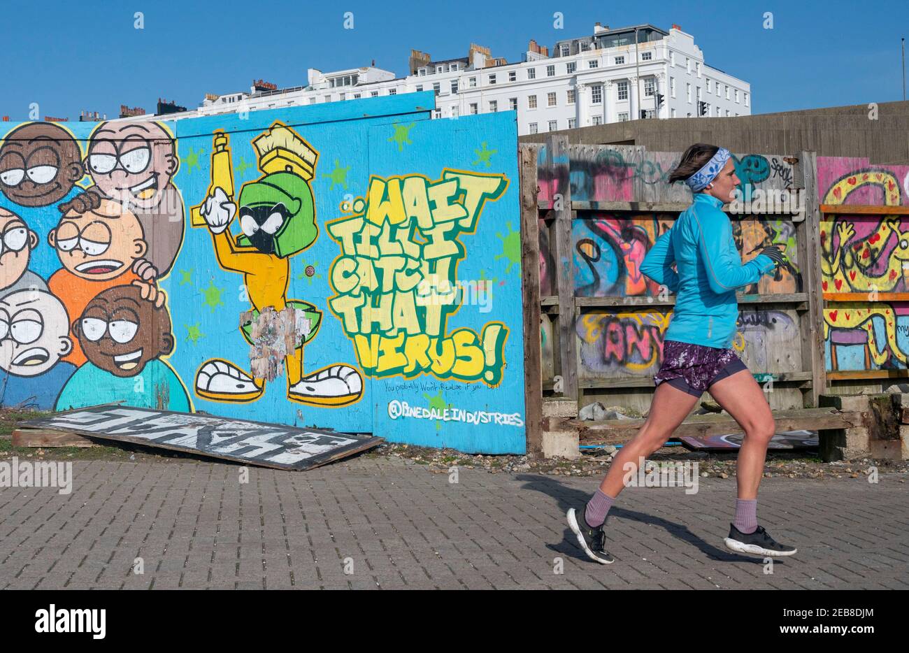 Brighton UK 12th February 2021 - EIN Läufer kommt an einem sonnigen, aber windigen Tag entlang der Südküste an einigen aktuellen Graffiti-Kunst in der Nähe von Brighton Marina vorbei : Credit Simon Dack / Alamy Live News Stockfoto