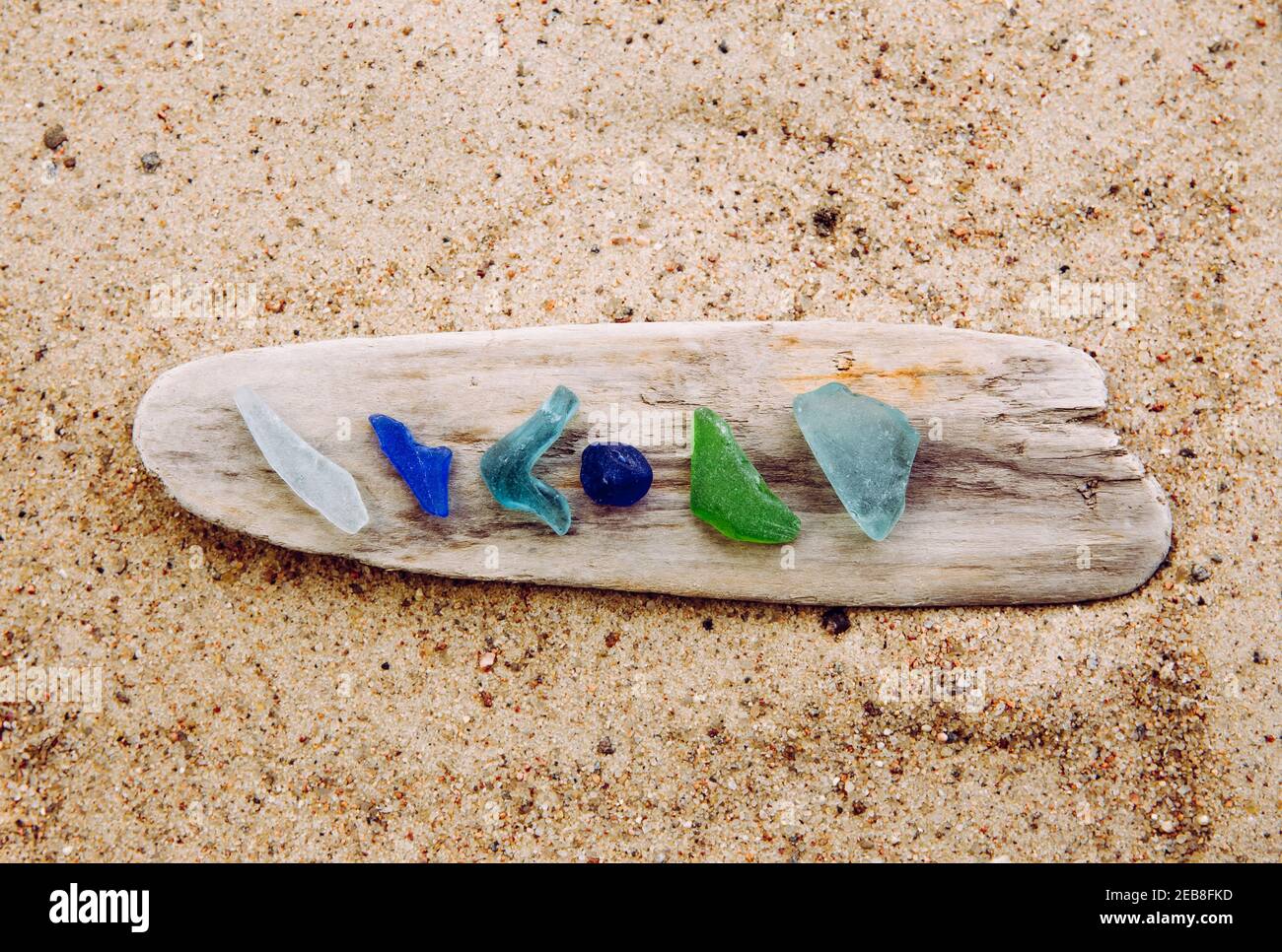 Verschiedene Farben blau, grün, weißes Meerglas oder Strandglas auf Treibholz im Strand auf Sand. Glas war einmal Flaschenstücke und jetzt ist das Meer gestolpert. Stockfoto