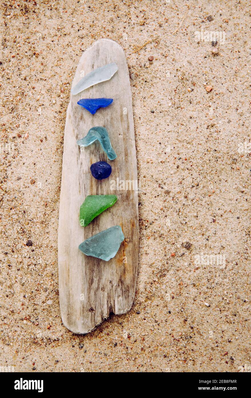 Verschiedene Farben blau, grün, weißes Meerglas oder Strandglas auf Treibholz im Strand auf Sand. Glas war einmal Flaschenstücke und jetzt ist das Meer gestolpert. Stockfoto