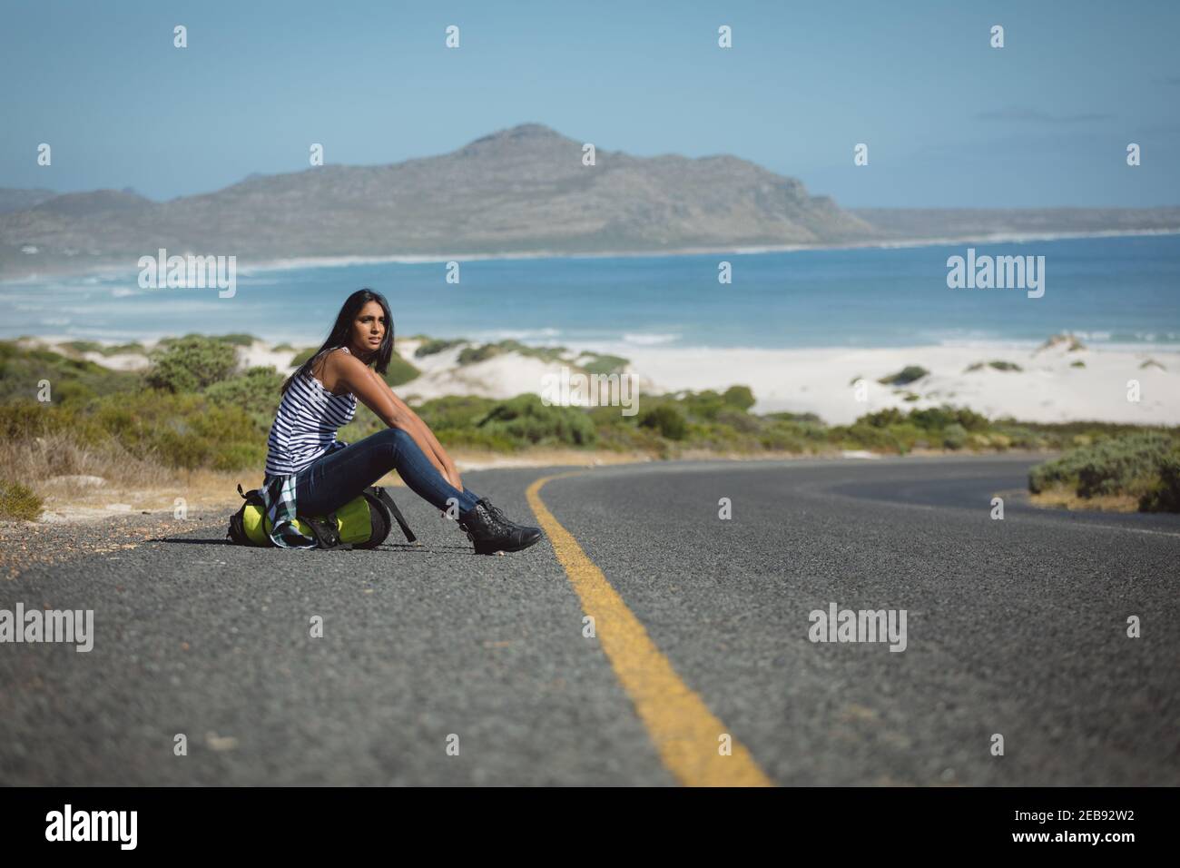 Gemischte Rasse Frau sitzt an der Straße und Anhalter Stockfoto