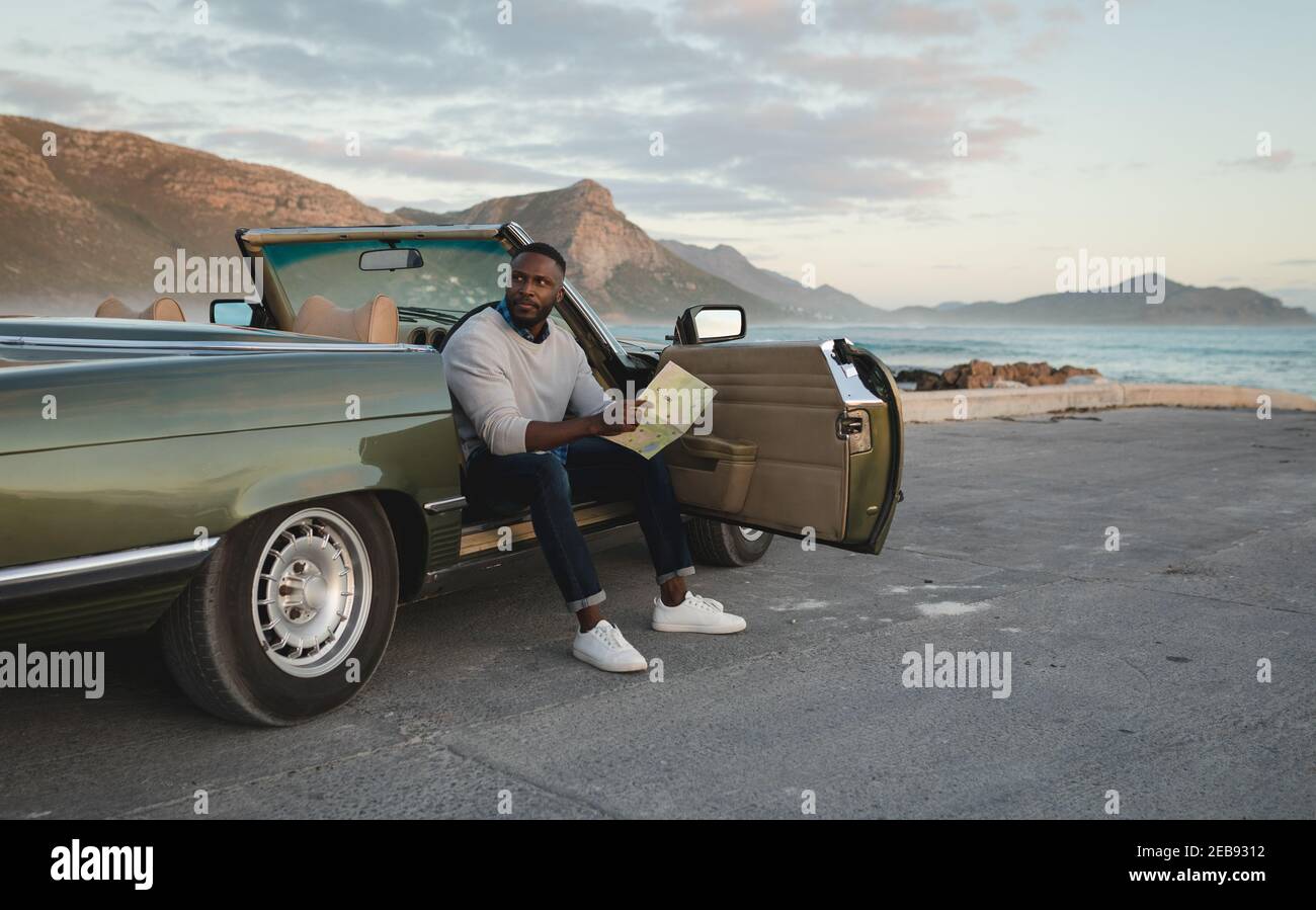 Afroamerikanischer Mann, der in einem Cabriolet sitzt und anschaut Karte Stockfoto