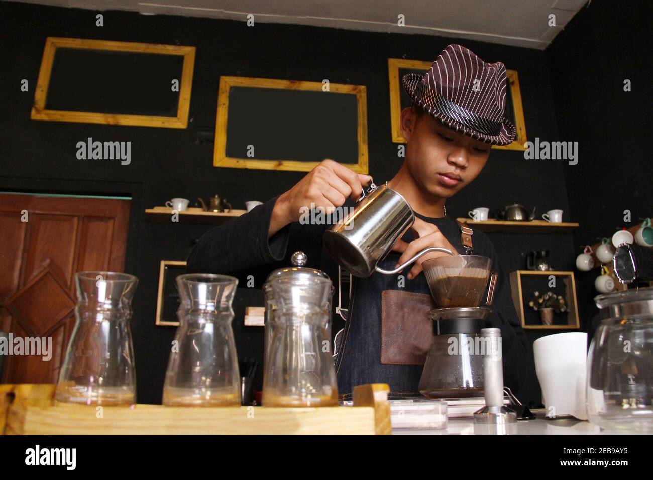 Indonesische Barista bereiten Kaffeegetränke für Kunden im Coffee Shop. Portrait eines Coffee Shop Mitarbeiter Kaffee an der Bar. Der Prozess der Stockfoto