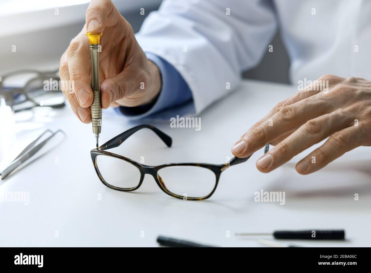Brillen Reparatur-Service - Optiker Reparatur Brillengestell mit Schraubendreher Stockfoto