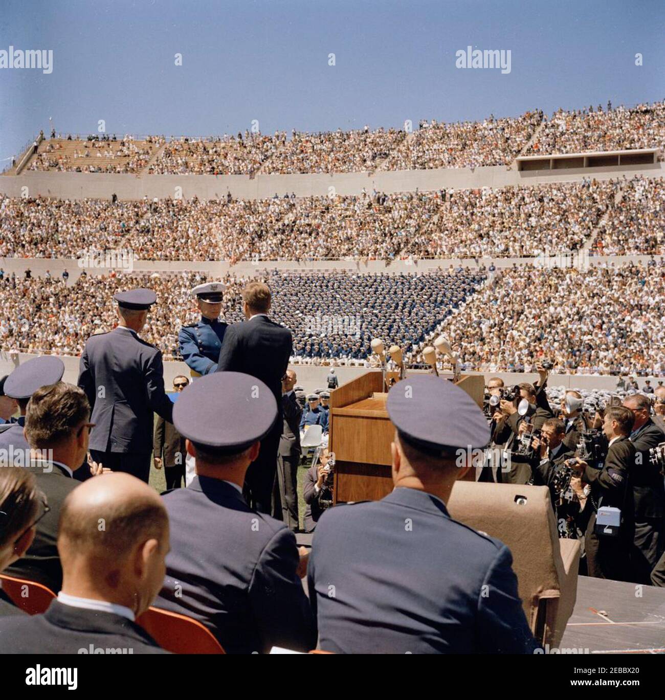 Reise in die westlichen Staaten: Präsident Kennedy an der U.S. Air Force (USAF) Academy, Colorado. Präsident John F. Kennedy (stehend auf speakeru0027s Plattform in der Mitte links, zurück zur Kamera) schüttelt die Hände mit einem nicht identifizierten Kadett während der Anfangsübungen für die fünfte Abschlussklasse der United States Air Force (USAF) Academy; Präsident Kennedy hielt eine Ansprache zu diesem Anlass. Falcon Stadium, USAF Academy, Colorado Springs, Colorado. Stockfoto