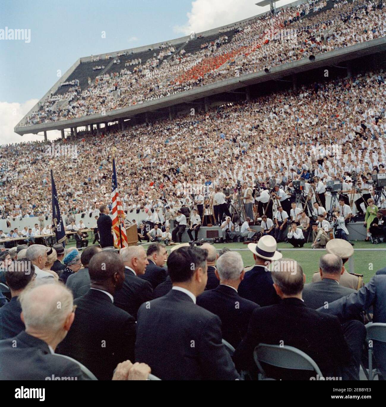 Besichtigung der NASA-Installationen: Houston, Texas, Autokolonne, Adresse an der Rice University, 9:34am Uhr. Präsident John F. Kennedy (links, an einem Rednerpult) hält Bemerkungen an der Rice University zu den nationu0027s Bemühungen in der Weltraumforschung. Pressevertreter sitzen links im Hintergrund, Fotografen versammeln sich rechts, Zuschauer beobachten von der Tribüne aus. Rice University Stadium, Houston, Texas. Stockfoto