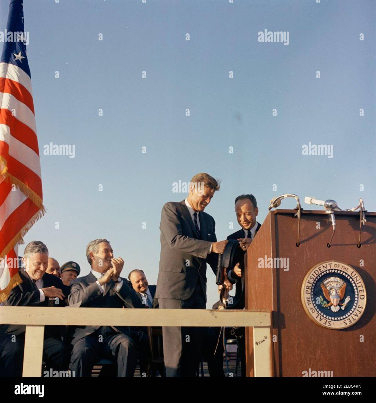 Reise nach Westen: El Paso, Texas. Präsident John F. Kennedy (Mitte) erhält Geschenke vom Bürgermeister von El Paso, Texas, Judson Williams (stehend hinter einem Rednerpult), während einer Zeremonie zu seinen Ehren am internationalen Flughafen von El Paso; Zu den Geschenken gehörten ein Paar Colt Pistolen im Kaliber .45, ein Texas Ranger Abzeichen, ein Texas Ranger Charme und der Schlüssel zur Stadt El Paso. Senator Ralph W. Yarborough (Texas) und Gouverneur von Texas, John Connally, sitzen in der ersten Reihe auf der linken Seite. El Paso, Texas. [Siehe auch MO 63,399.1, u0022Texas Ranger Peacemakers Colt Pistolsu0022; MO 63,399.2a, u0022Texas Ranger Badgeu00 Stockfoto