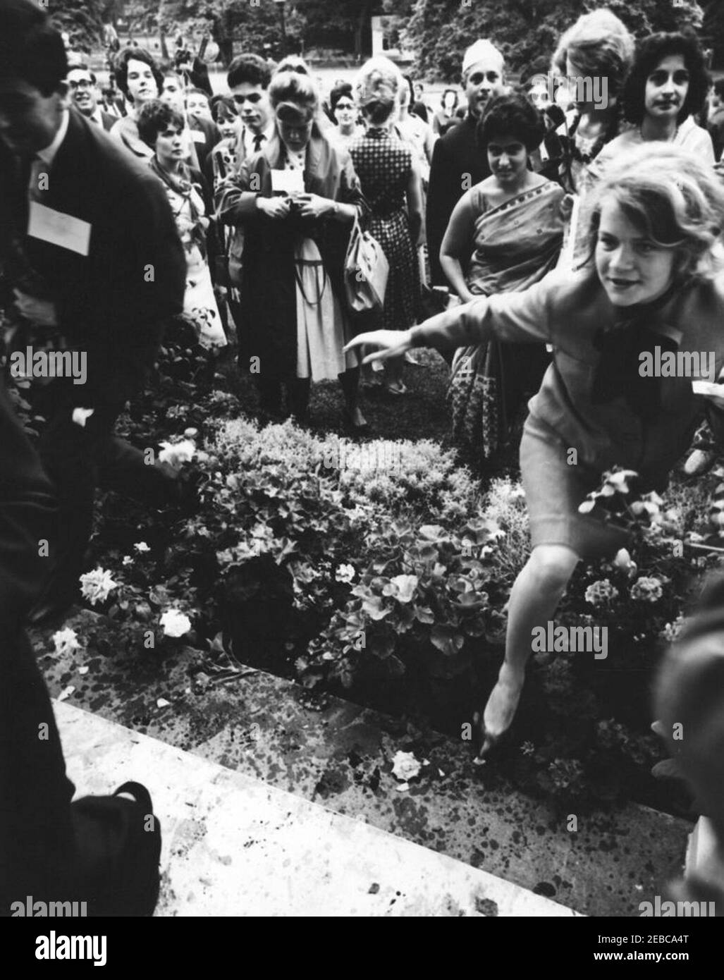 Besuch der Teilnehmer des Experiments in International Living, 12:00pm Uhr. Eine nicht identifizierte Frau (ganz rechts) klettert über eine Hecke auf dem Westflügel Rasen des Weißen Hauses, während eines Besuches der Teilnehmer am Experiment in International Living Programm; andere Teilnehmer, darunter Asha Mirchandani aus Indien (fünfte von rechts), stehen im Hintergrund. Washington, D.C. Stockfoto