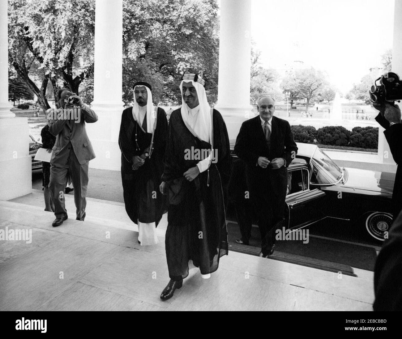 Mittagessen zu Ehren von Faisal ibn Abdul Aziz Al Saud, Kronprinz von Saudi-Arabien, 1:05pm Uhr. Kronprinz von Saudi-Arabien, Faisal ibn Abdul Aziz Al Saud, kommt im Weißen Haus zu einem Mittagessen zu seinen Ehren an. Von links nach rechts: Nicht identifizierter Filmfotograf (Gesicht von der Kamera verdeckt); Botschafter Saudi Arabiens, Scheich Abdullah Al-Khayyal; Kronprinz Faisal; US-Stellvertretender Protokollführer William J. Tonesk. North Portico, White House, Washington, D.C. Stockfoto