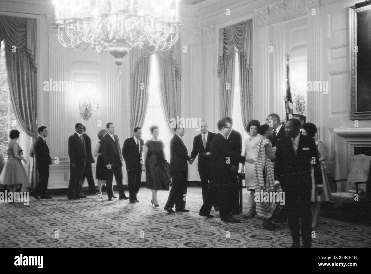 Diplomatischer Empfang, 6:00pm Uhr. Präsident John F. Kennedy, First Lady Jacqueline Kennedy und andere begrüßen die Gäste in der Empfangsleitung bei einem diplomatischen Empfang im Weißen Haus. Rechts: Chef des Protokolls Angier Biddle Duke (Händeschütteln mit einem nicht identifizierten Mann), Präsident Kennedy (meist versteckt), Frau Kennedy, Vizepräsident Lyndon B. Johnson, Lady Bird Johnson (teilweise versteckt). Alle anderen sind nicht identifiziert. State Dining Room, White House, Washington, D.C. Stockfoto