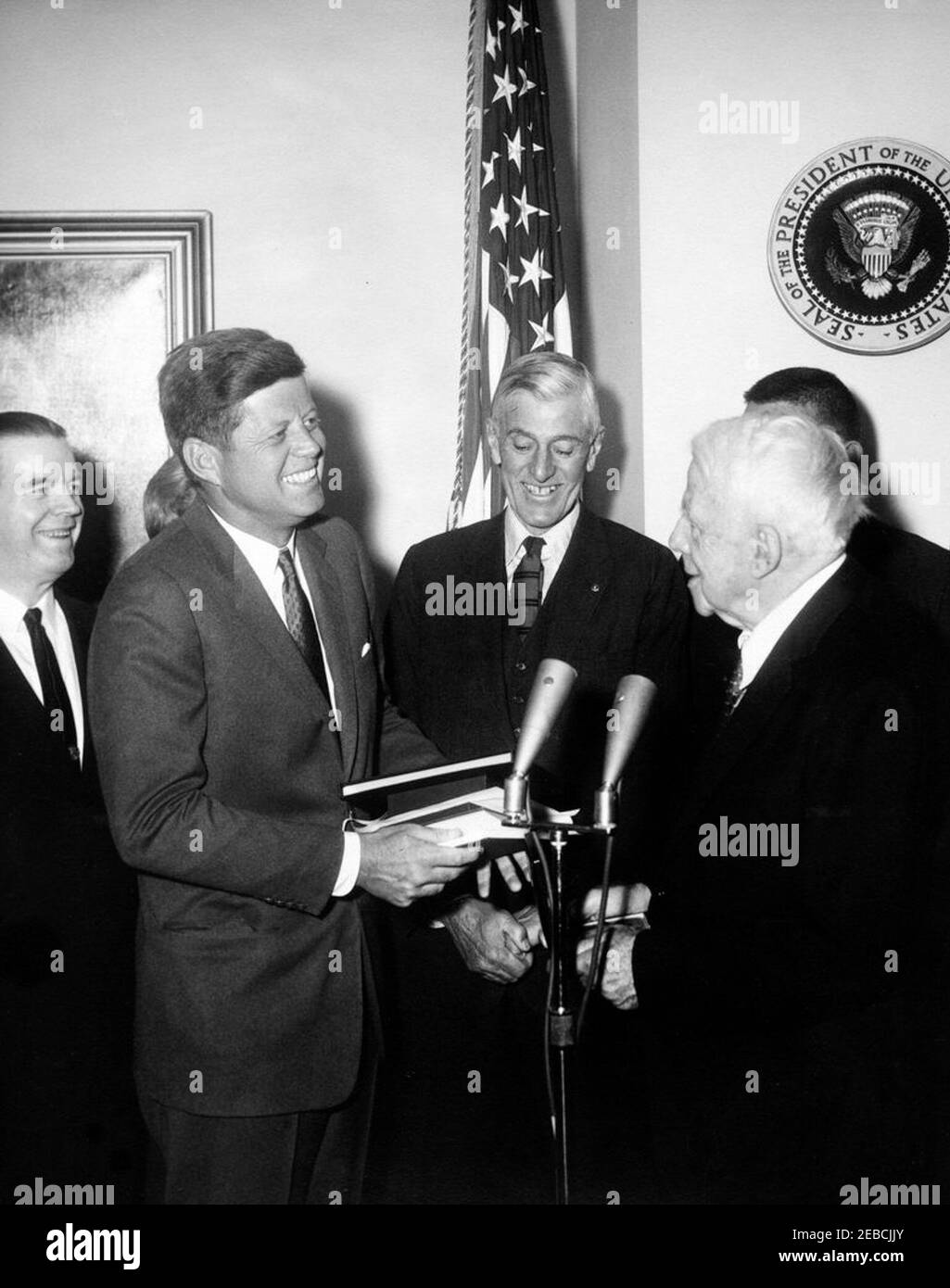 Übergabe einer Congressional Gold Medal an Robert Frost, 12:00pm. Präsident John F. Kennedy überreicht dem Dichter Robert Frost eine Goldmedaille des Kongresses im Fish Room (Conference Room), White House, Washington, D.C. (L-R), dem Vertreter James A. Burke aus Massachusetts; Erma Lee Udall (meist versteckt; Ehefrau des Innenministers Stewart Udall); Präsident Kennedy; Senator Leverett Saltonstall aus Massachusetts; Robert Frost; Sekretär Udall (meist versteckt hinter Frost). Stockfoto