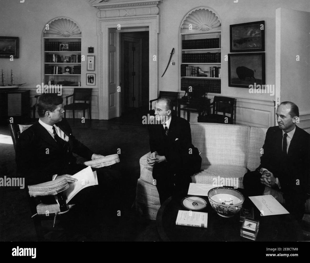 Treffen mit dem Botschafter von Syrien, Omar Abu-Riche, 12:05pm Uhr. Präsident John F. Kennedy (im Schaukelstuhl) trifft sich mit Botschafter in den Vereinigten Staaten aus Syrien Omar Abu-Riche. Rechts sitzt der Chef des US-Protokolls Angier Biddle Duke. Oval Office, White House, Washington, D.C. Stockfoto