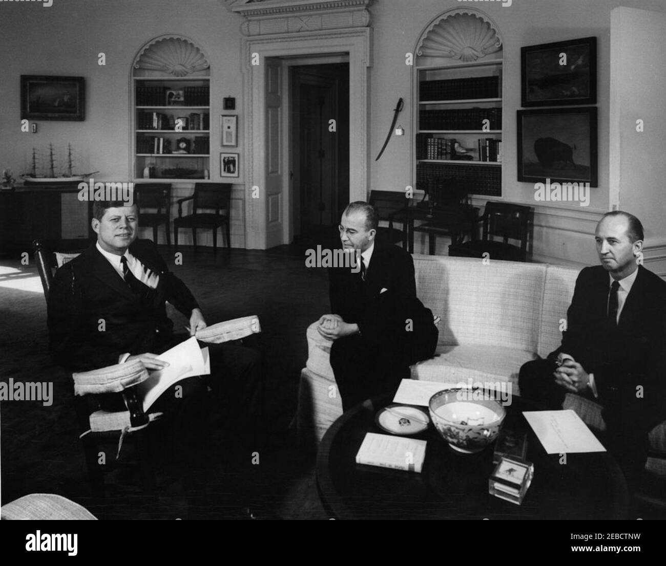 Treffen mit dem Botschafter von Syrien, Omar Abu-Riche, 12:05pm Uhr. Präsident John F. Kennedy (im Schaukelstuhl) trifft sich mit Botschafter in den Vereinigten Staaten aus Syrien Omar Abu-Riche. Rechts sitzt der Chef des US-Protokolls Angier Biddle Duke. Oval Office, White House, Washington, D.C. Stockfoto