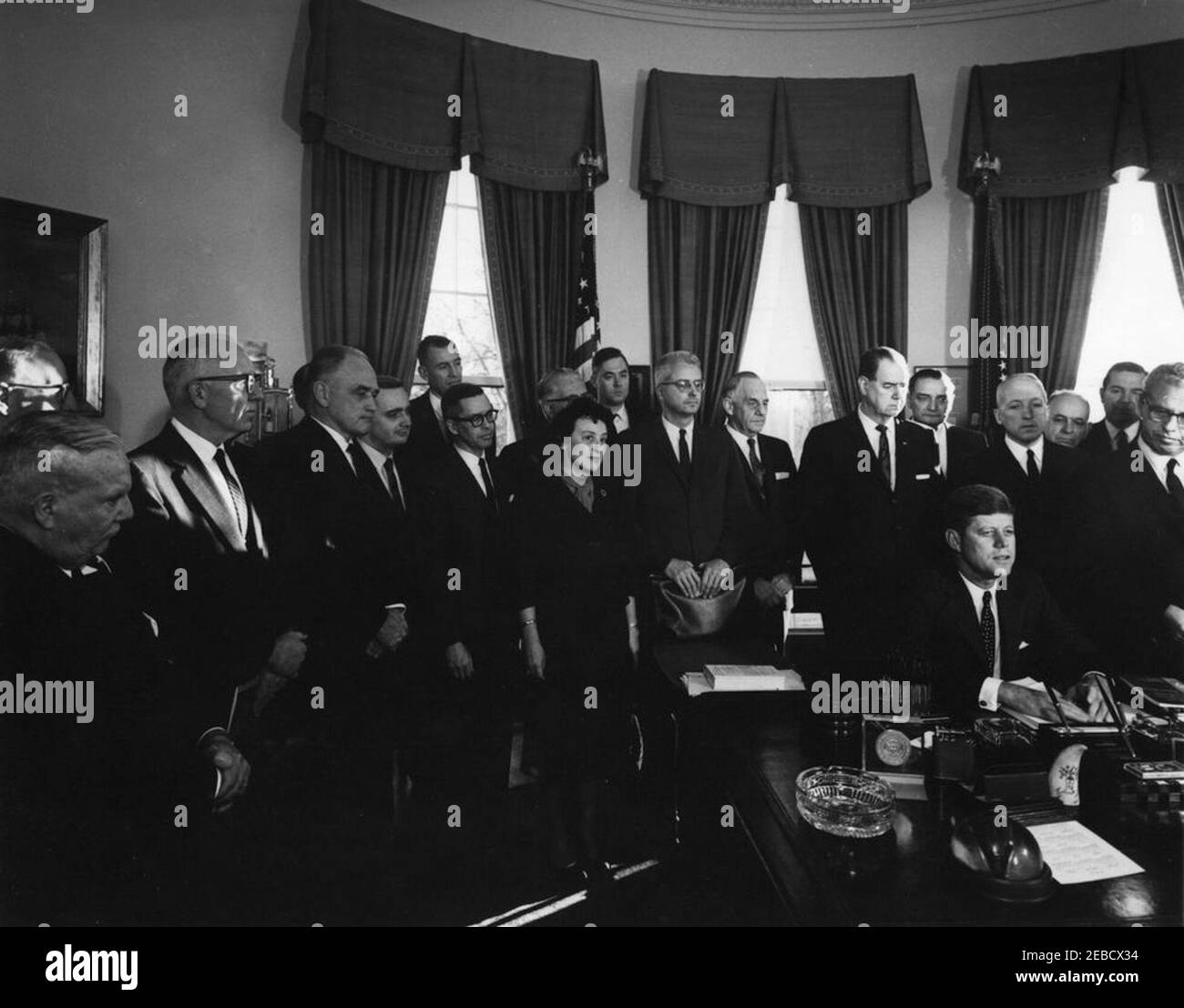 Unterzeichnung des Executive Order, u201cTask Kraft für die Mitarbeiter-Management-Beziehungen im Bundesdienst,u201d 4:10pm. Präsident John F. Kennedy unterzeichnet Executive Order für die Task Force on Employee-Management Relations im Bundesdienst. Stehend, L-R: Sechs nicht identifizierte Männer; Direktor des Büros des Haushalts, David E. Bell (im Rücken, vor dem Fenster); Berater des New York City Department of Labor, Ida Klaus; nicht identifizierter Mann im Rücken; Vorsitzender der Kommission für den öffentlichen Dienst, John W. Macy, Jr.; Senator Frank Carlson (Kansas); Senator Olin D. Johnston (South Carolina); nicht identifiziert; Pos. Stockfoto