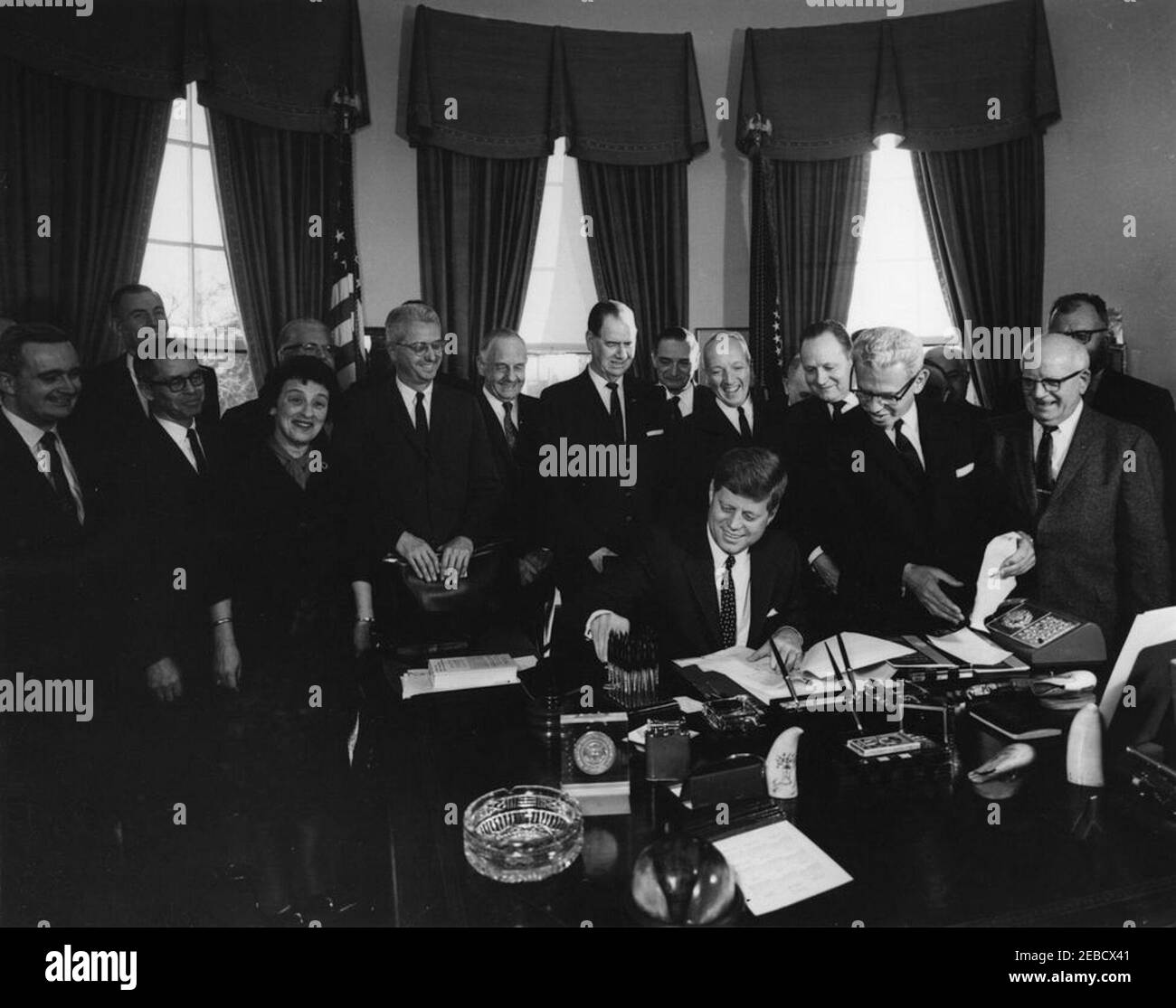 Unterzeichnung des Executive Order, u201cTask Kraft für die Mitarbeiter-Management-Beziehungen im Bundesdienst,u201d 4:10pm. Präsident John F. Kennedy unterzeichnet Executive Order für die Task Force on Employee-Management Relations im Bundesdienst. Standing, L-R: Zwei nicht identifizierte Männer; Direktor des Bureau of the Budget, David E. Bell (im Rücken); Berater des New York City Department of Labor, Ida Klaus; Vorsitzender der Kommission für den öffentlichen Dienst, John W. Macy, Jr.; Senator Frank Carlson (Kansas); Senator Olin D. Johnston (South Carolina); nicht identifiziert; Postmaster General, J. Edward Day; nicht identifiziert; Stockfoto