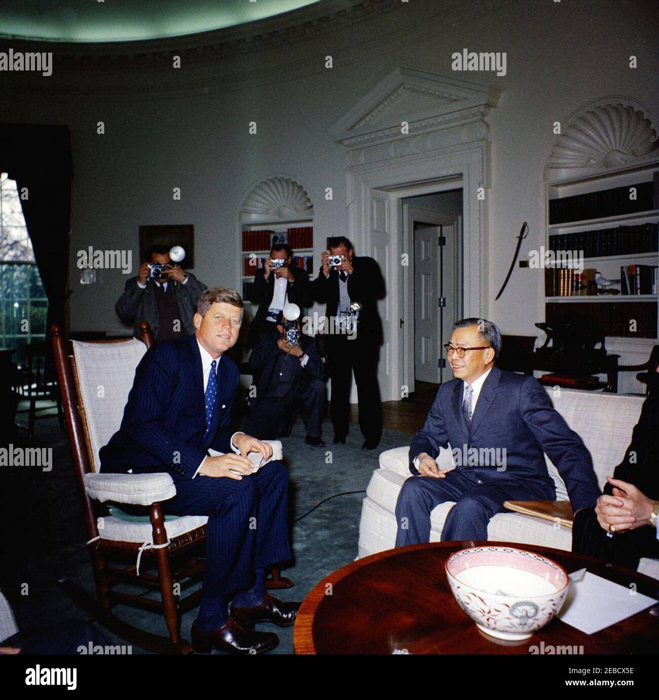 Treffen mit dem Botschafter von China, Dr. Tingfu F. Tsiang, 12:05pm Uhr. Präsident John F. Kennedy (im Schaukelstuhl) trifft sich mit dem neu ernannten Botschafter in den Vereinigten Staaten aus China, Tingfu F. Tsiang. Rechts sitzt der Chef des US-Protokolls Angier Biddle Duke, Fotografen beobachten es. Stockfoto