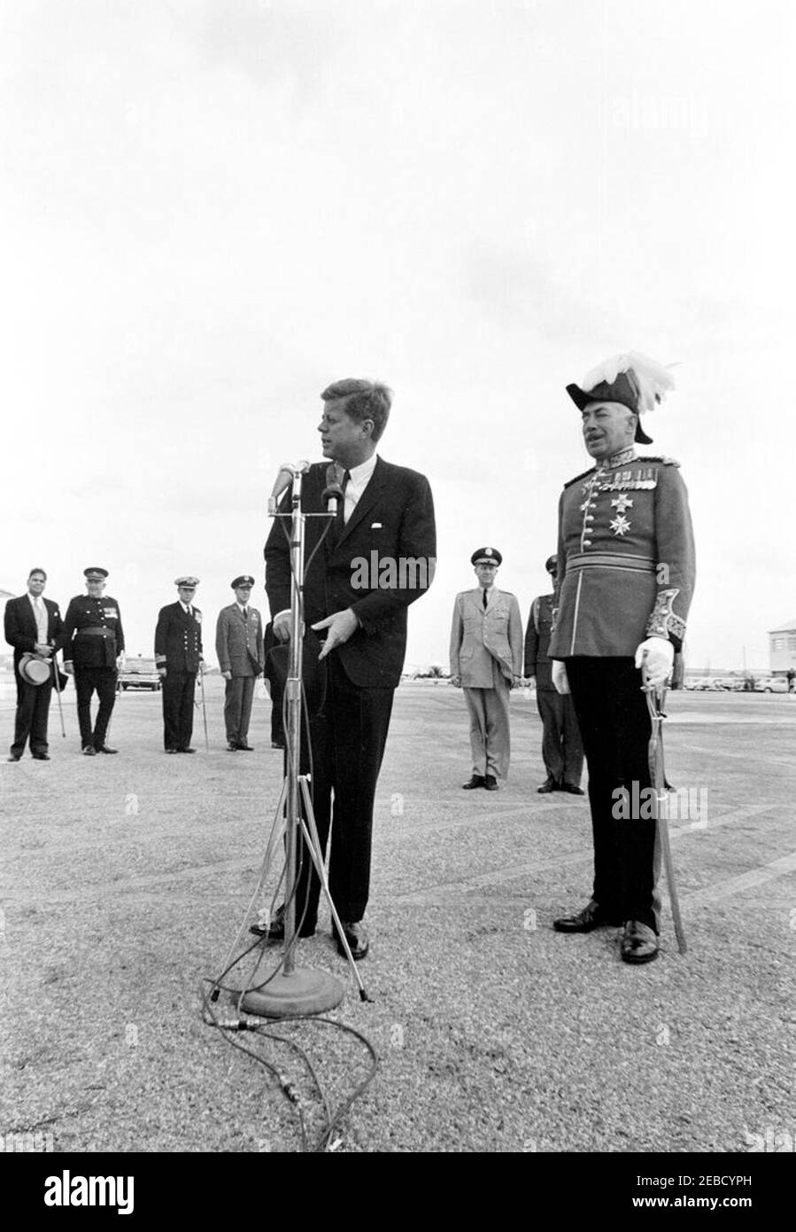 Reise nach Bermuda: Ankunft auf der Kindley Air Force Base, Bermuda, 12:55pm Uhr. Präsident John F. Kennedy (mit Hut) spricht die Menge bei seiner Ankunft in Bermuda von Palm Beach, Florida. Rechts steht der Gouverneur von Bermuda, Generalmajor Sir Julian Gascoigne. Militärische Seite an Präsident Kennedy General Chester V. Clifton und Air Force Aide an den Präsidenten Brigadier General Godfrey T. McHugh (teilweise versteckt) stehen im Hintergrund zwischen dem Präsidenten und Gouverneur Gascoigne. Alle anderen sind nicht identifiziert. Kindley Air Force Base, St. Davidu2019s Island, Bermuda. Stockfoto