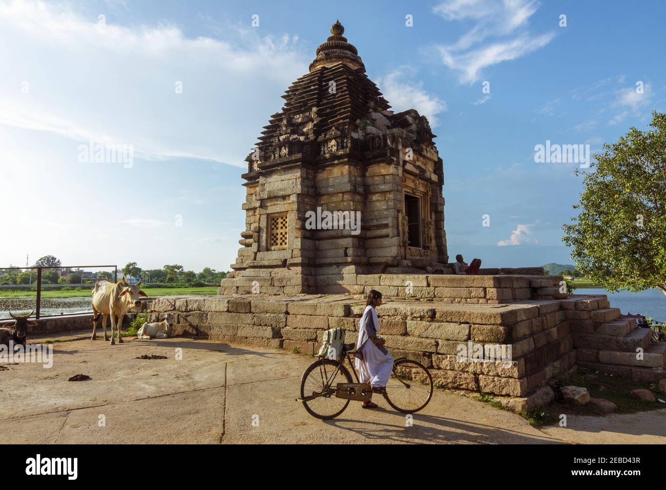 Khajuraho, Madhya Pradesh, Indien : EIN Mädchen mit einem Fahrrad steht neben dem Brahma Tempel am Ufer des Narora Sagar See, Teil des östlichen Stockfoto