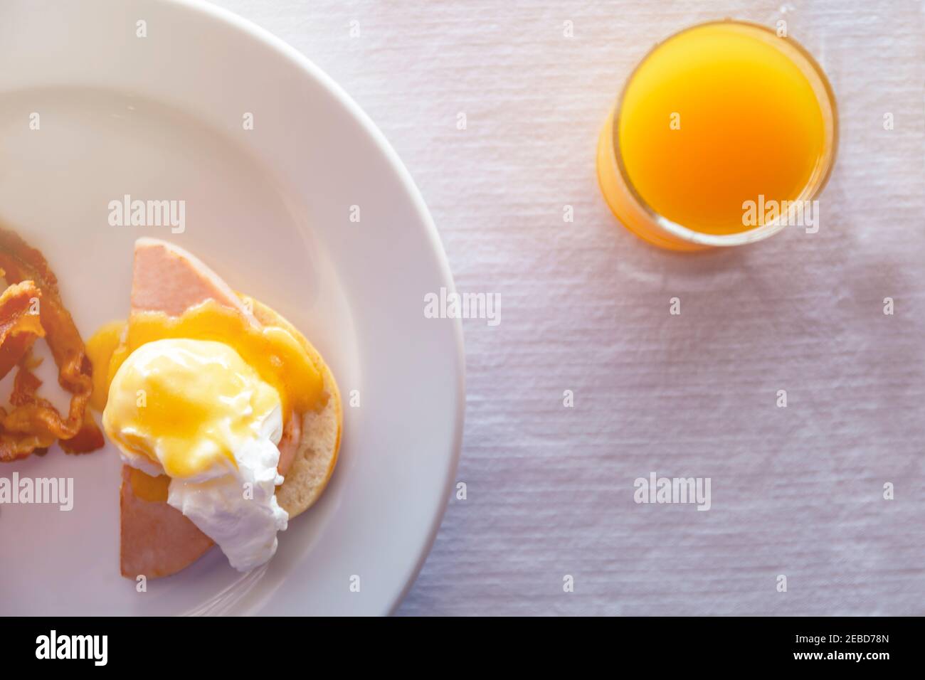 Draufsicht close up Orangensaft im Glas und Ei benedict Frühstück auf weißem Tischdecke. Essen und Trinken Konzept.Draufsicht Frühstück mit pochierten Eiern ro Stockfoto