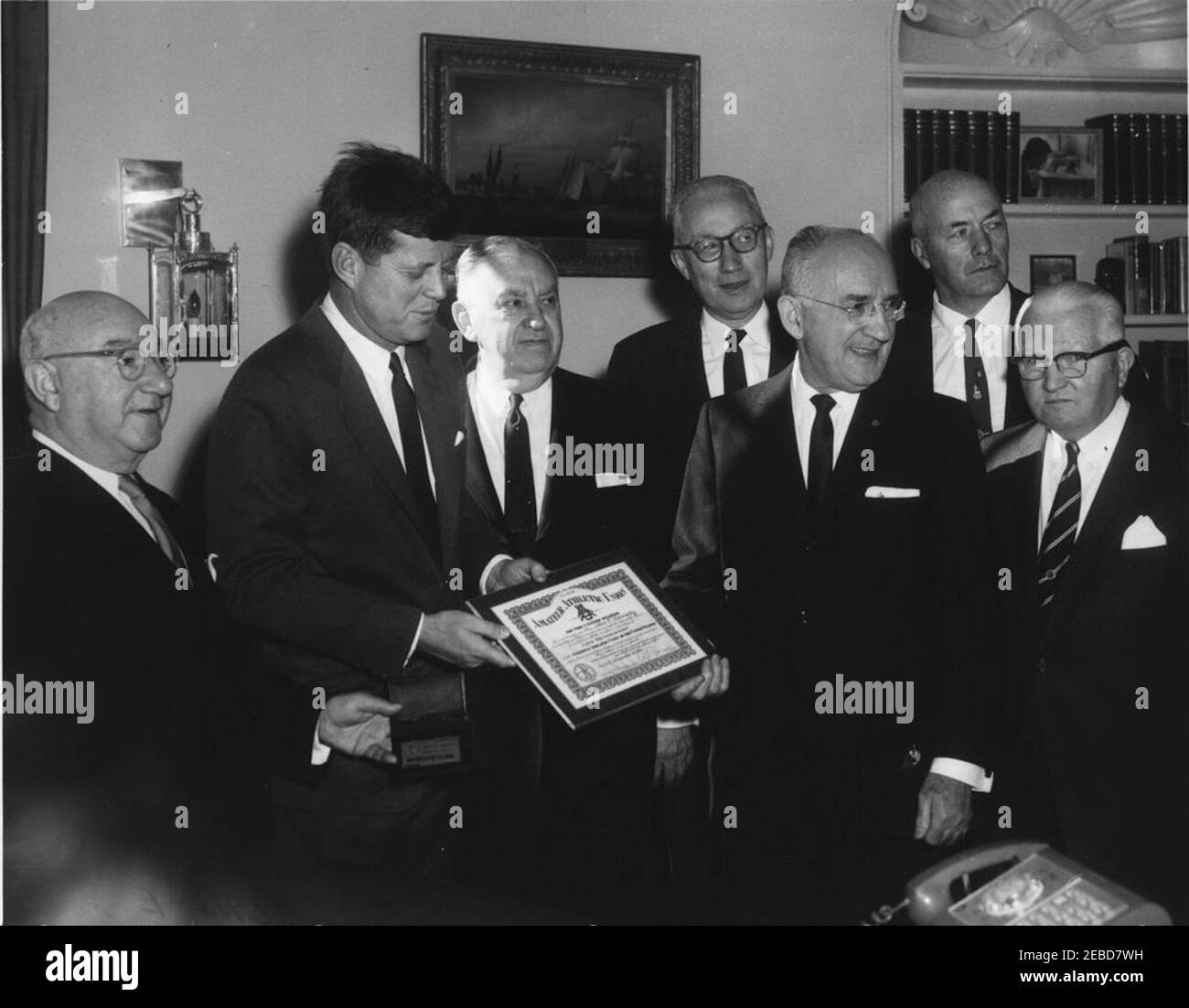 Präsentation einer Amateur Athletic Union (AAU) Life Membership Plakette an Präsident Kennedy, 12:03pm. Präsident John F. Kennedy wird mit einer Amateur Athletic Union (AAU) Life Membership Plakette überreicht. (L-R) Ed Rosenblum, Vorsitzender des AAU Life Membership Committee; Präsident Kennedy; Charles L. Ornstein, Vorsitzender der AAU; James F. Simms, Secretary Treasurer der AAU; Nick J. Barack, Präsident der AAU; Bob Hoffman, Trainer der United States Olympic Weight Lifting Team; Dan Ferris, Ehrensekretär der AAU. Oval Office, White House, Washington, D.C. Stockfoto