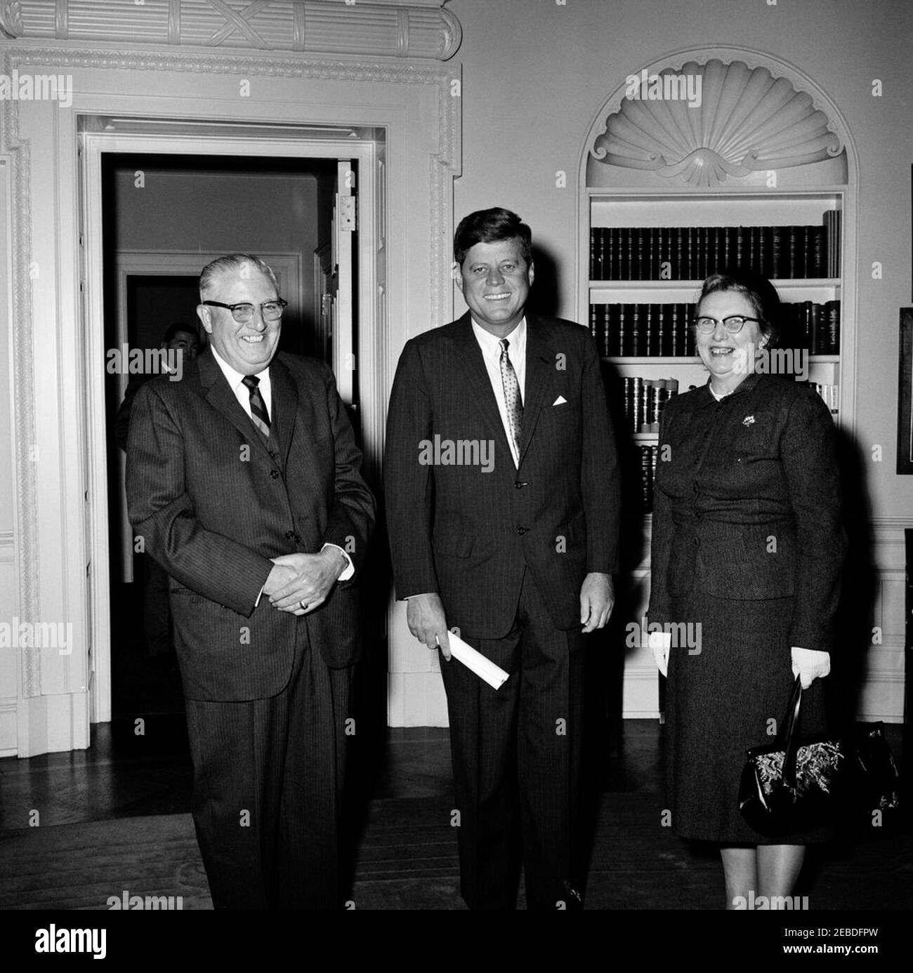 Präsident Kennedy mit Besuchern Hugh Thompson. Präsident John F. Kennedy trifft sich mit Besuchern. (L u2013 R): Hugh Thompson, Regional Director (New England) of American Federation of Labor and Congress of Industrial Organization (AFL-CIO); Präsident Kennedy; Frau Thompson. Sonderassistent des Präsidenten Kenneth P. Ou2019Donnell im Hintergrund. Oval Office, White House, Washington, D.C. Stockfoto
