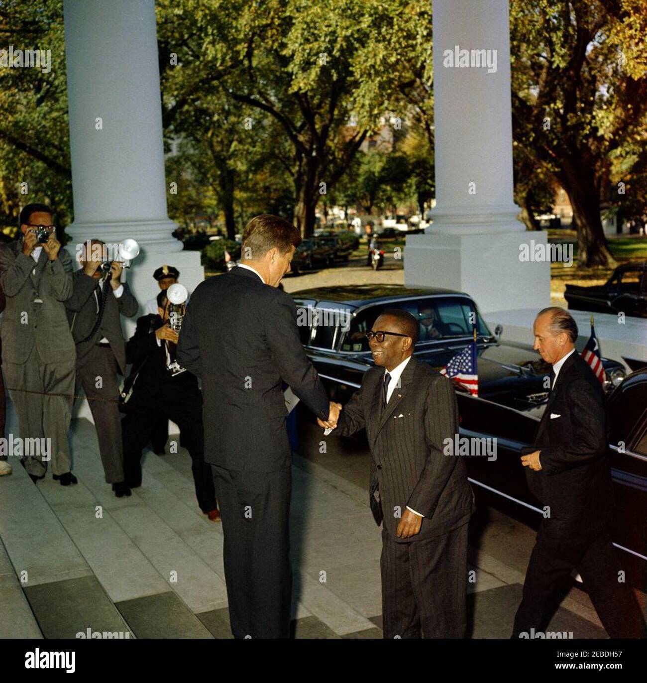 Mittagessen zu Ehren von William Vacanarat Shadrach Tubman, Präsident von Liberia, 1:00 Uhr. Mittagessen zu Ehren von William V.S. Tubman, Präsident von Liberia. (L u2013 R): Präsident John F. Kennedy (zurück zur Kamera); Präsident Tubman; Protokollchef Angier Biddle Duke. Verschiedene nicht identifizierte Reporter und Fotografen im Hintergrund. North Portico, White House, Washington, D.C. Stockfoto