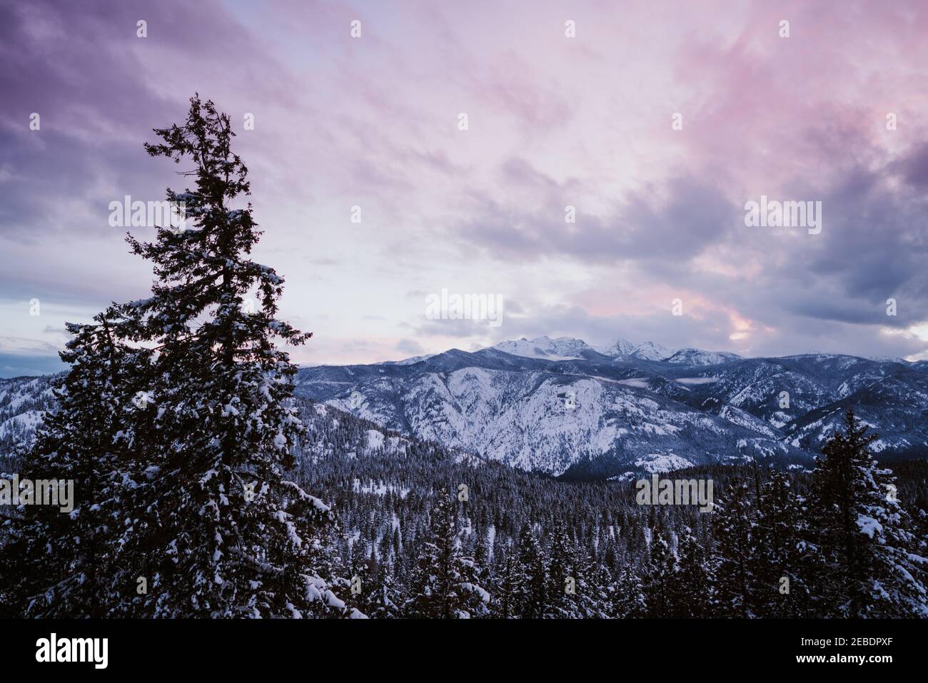 Sonnenuntergang über schneebedeckten Bergen mit blauen und violetten Farbtönen Stockfoto