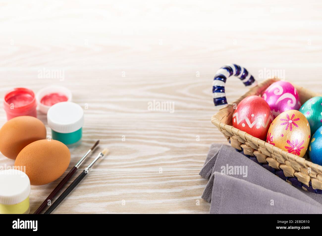 Bunte ostern gemalt handgemachte Eier, Farben und Pinsel. Festlicher Osterrahmen aus Eiern, Farben und Pinsel auf weißem Holzhintergrund mit Kopie Stockfoto
