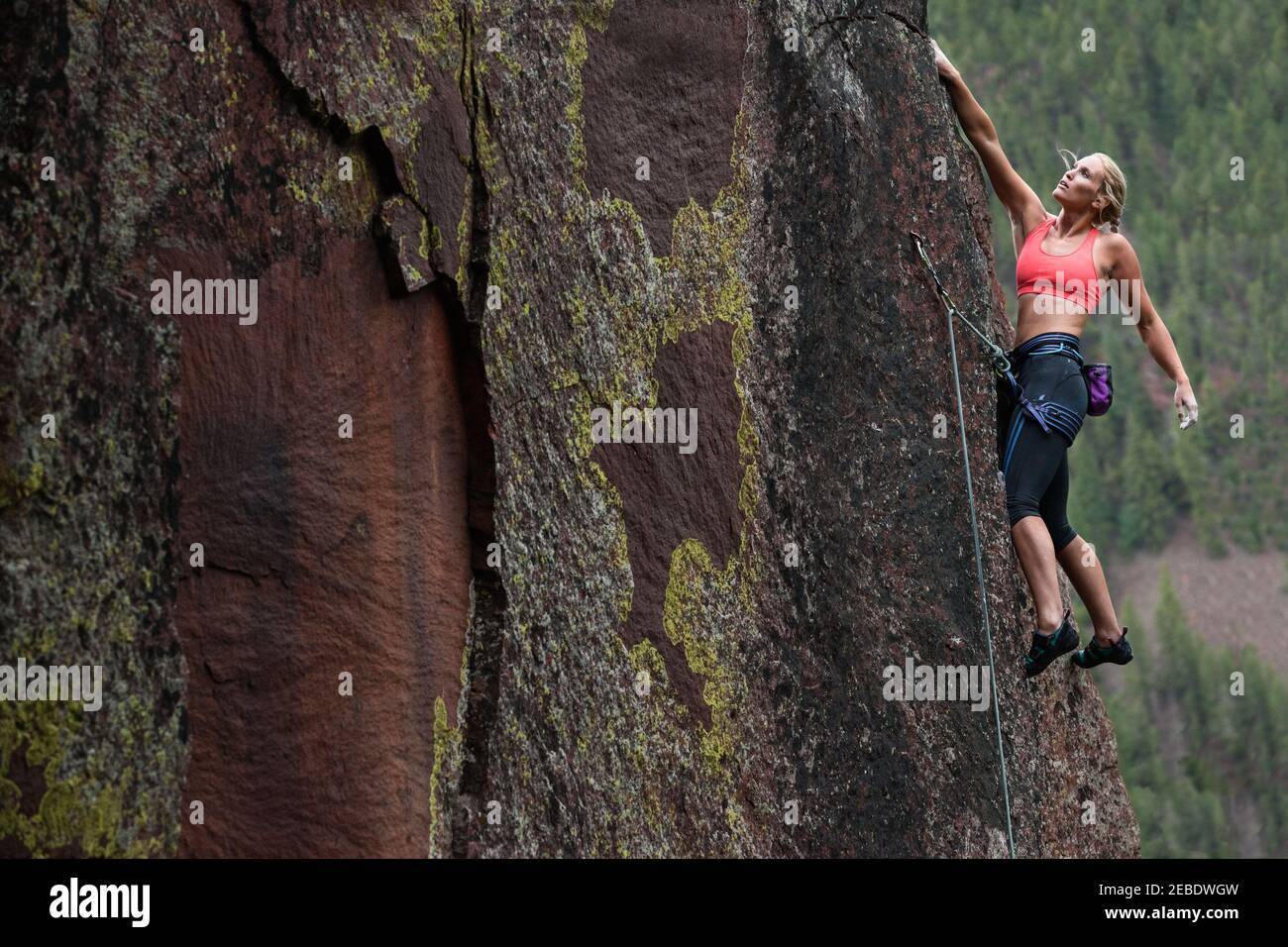 Weibliche Klettererin mit windgeblasenem Haar ruht beim Führen Route Stockfoto