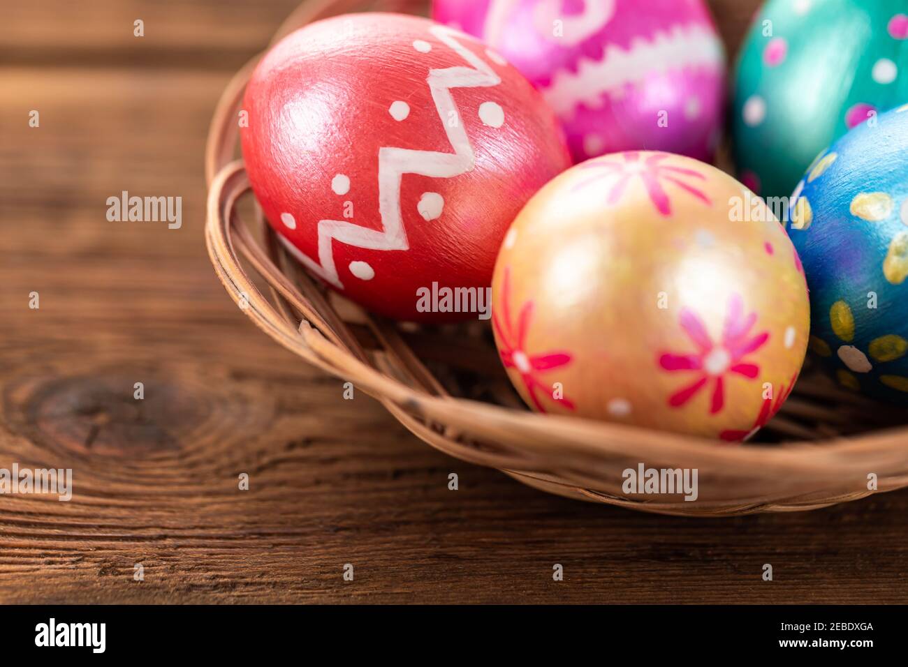 Fünf ostereier trendy Farben tiefblau, grün, orange, magenta und golden dekoriert in Korb auf alten Holztisch. Platz für Text kopieren. Stockfoto