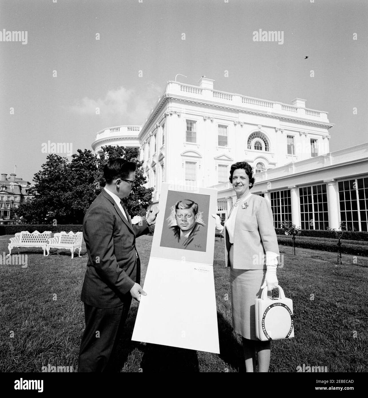 Präsentation eines Gemäldes von Präsident Kennedy von Frau G. A. Christian von Georgien (John J. McNally). Mrs. G.A. Christian präsentiert ein Gemälde von Präsident John F. Kennedy dem Mitarbeiter John J. u0022Jacku0022 McNally im East Garden, White House, Washington, D.C. Stockfoto