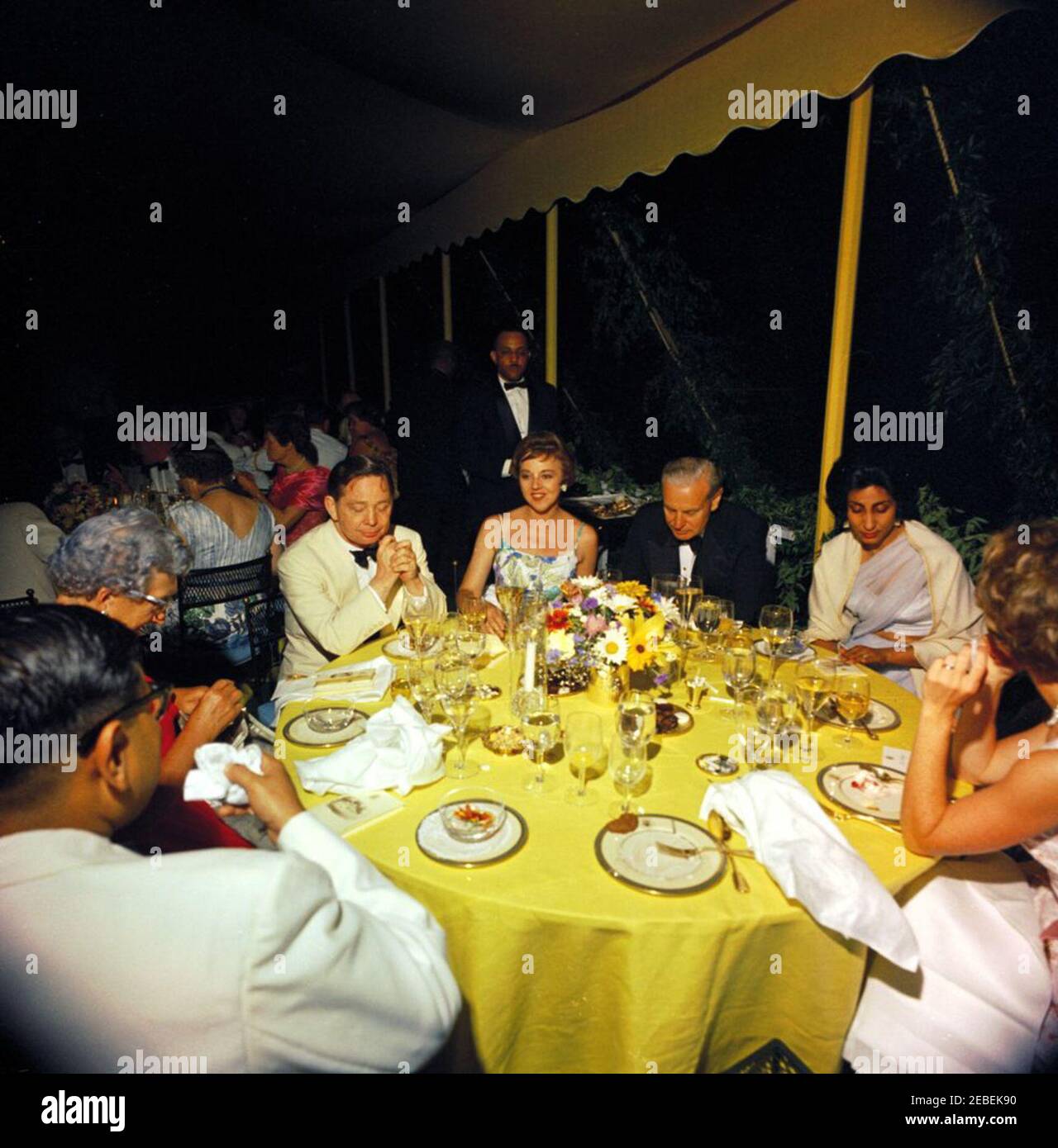Abendessen am Berg Vernon zu Ehren von Muhammad Ayub Khan, Präsident Pakistans, 7:45pm Uhr. Staatsessen zu Ehren von Präsident Mohammad Ayub Khan von Pakistan. (Im Uhrzeigersinn von oben): Anne Bodine Clifton, Ehefrau von Military Aide an den Präsidenten General Chester V. Clifton; Walter Hoving, Eigentümer der Tiffany u0026 Company; Frau Syed Haider Raza, Ehefrau des Air Vice Marshal der pakistanischen Luftwaffe; Anne Sidey, Ehefrau des Journalisten Hugh Sidey; Nsim Ahmed; Frau John Taber, Ehefrau des New Yorker Kongressabgeordneten John Taber; Oklahoma Kongressabgeordneter Carl Albert. Festzelt; Mount Vernon, Virginia Stockfoto