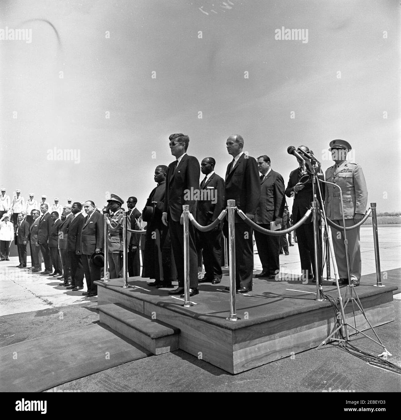 Ankunftszeremonie für Fulbert Youlou, Präsident der Republik Kongo (Brazzaville), 12:00pm Uhr. Ankunftszeremonien für den Präsidenten der Republik Kongo (Brazzaville) Fulbert Youlou. Auf Plattform (L-R): Präsident Youlou, Präsident John F. Kennedy (mit Sonnenbrille), Botschafter der Republik Kongo (Brazzaville) Emmanuel Damongo Dadet, Staatssekretär Dean Rusk, Dolmetscher des US-Außenministeriums Edmund S. Glenn, Chef des Außenministeriums für Protokoll Angier Biddle Duke (hinter Mikrofonen), Und Kommandant des United States Marine Corps General David M. Shoup. Auch ich eingeschlossen Stockfoto