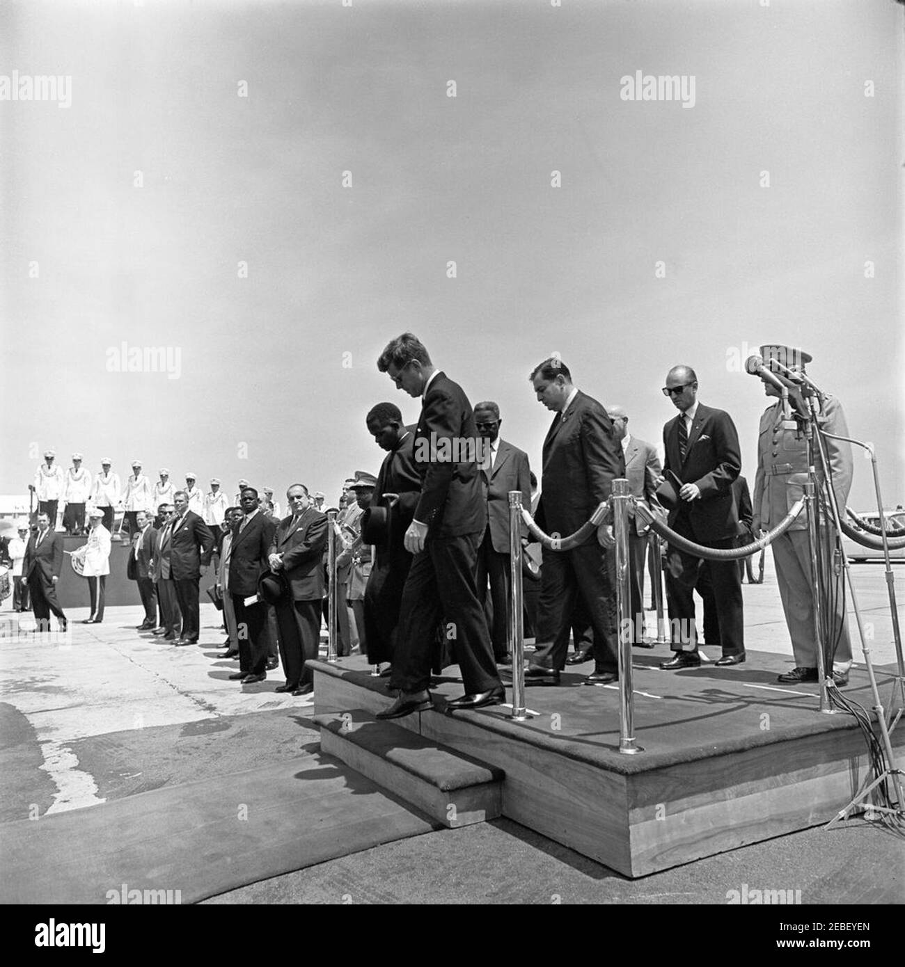 Ankunftszeremonie für Fulbert Youlou, Präsident der Republik Kongo (Brazzaville), 12:00pm Uhr. Ankunftszeremonien für den Präsidenten der Republik Kongo (Brazzaville) Fulbert Youlou. Auf der Plattform (L-R): Präsident Youlou, Präsident John F. Kennedy, nicht identifizierter Mann, Dolmetscher des US-Außenministeriums Edmund S. Glenn, Protokollchef Angier Biddle Duke (mit Hut) und Kommandant des US-Marine Corps General David M. Shoup (hinter Mikrofonen). Auch in der Fotografie enthalten und stehen auf der linken Seite der Plattform sind Assistant Secretary of State for Stockfoto