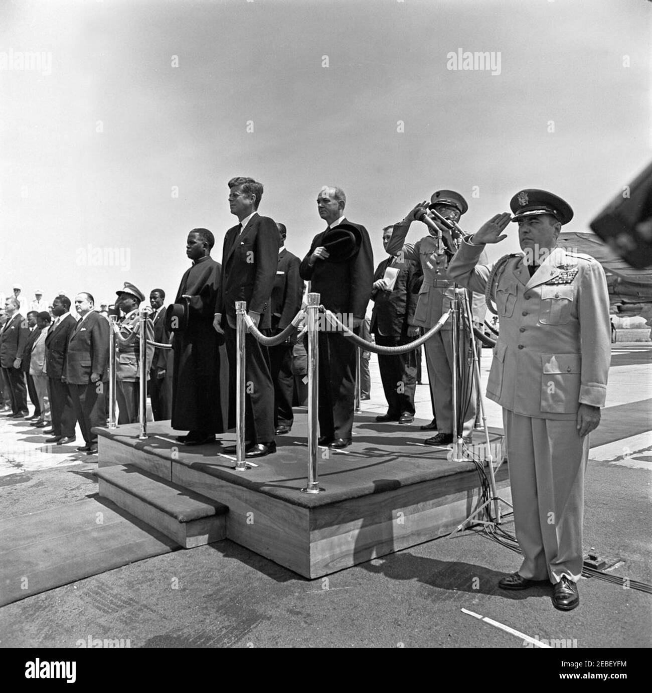 Ankunftszeremonie für Fulbert Youlou, Präsident der Republik Kongo (Brazzaville), 12:00pm Uhr. Ankunftszeremonien für den Präsidenten der Republik Kongo (Brazzaville) Fulbert Youlou. Auf der Plattform (L-R): Präsident Youlou, Präsident John F. Kennedy, Botschafter der Republik Kongo (Brazzaville) Emmanuel Damongo Dadet, Staatssekretär Dean Rusk (mit Hut), Dolmetscher des US-Außenministeriums Edmund S. Glenn (teilweise versteckt), Chef des Außenministeriums des Protokolls Angier Biddle Duke (hinter General Shoup), Und Kommandant des United States Marine Corps General David M. Shoup Stockfoto